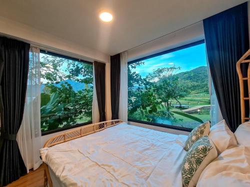 a bedroom with a bed and a large window at Pupah Kanna Pua-ปู๋ ป๋าล์ คันนา ปัว in Pua