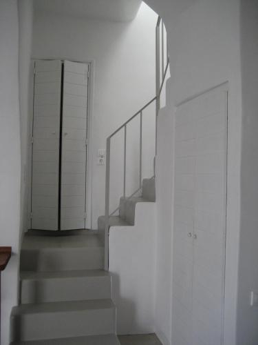 a staircase in a house with white walls and a door at Chora Elegant Traditional House in Amorgos