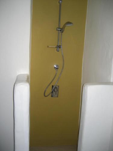 a bathroom with a shower in a yellow wall at Chora Elegant Traditional House in Amorgos