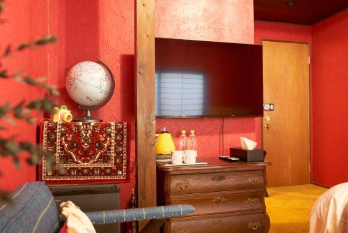 a bedroom with a red wall with a wooden dresser and a mirror at HOTEL Clam Chowder in Kyoto