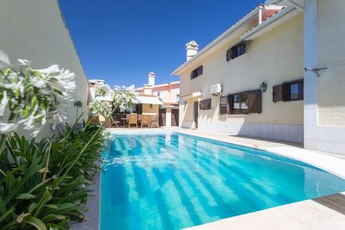 a swimming pool in front of a house at Aroeira Sunny Villa - Heated Pool extra cost in Amora