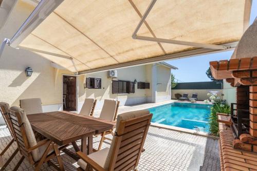 a patio with a wooden table and chairs and a swimming pool at Aroeira Sunny Villa - Heated Pool extra cost in Amora