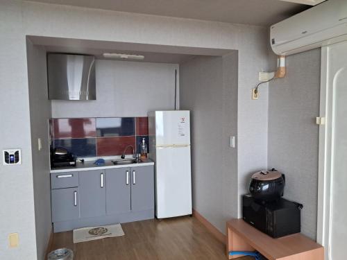 a kitchen with a white refrigerator in a room at Namhae Beach Hotel in Namhae