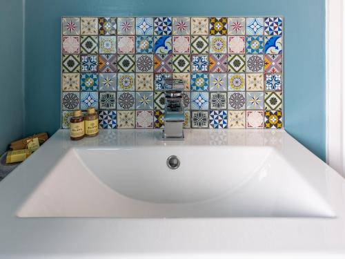 a white sink in a bathroom with a tile wall at The George Country Inn, Wath in Wath