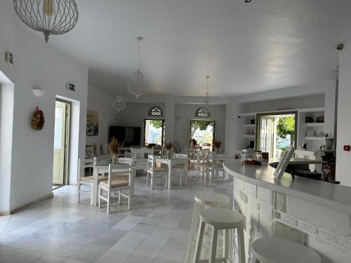 ein Esszimmer mit weißen Stühlen und einer Bar in der Unterkunft Artemis Hotel in Antiparos