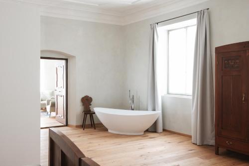 ein Badezimmer mit einer großen weißen Badewanne und einem Fenster in der Unterkunft Ansitz Layshof Apartment Erlebach in Meran