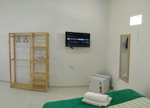 a room with a bed and a tv on the wall at pousada beira mar suites São Bento in Maragogi
