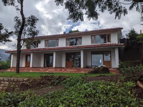 a white house with a tree in front of it at Moksha at Infinity Valley in Kotagiri