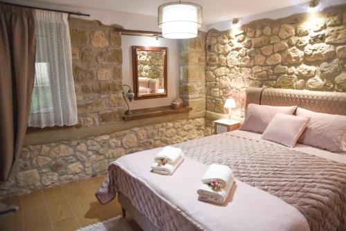 a bedroom with a bed and a stone wall at Elen's Suites Pramanta in Pramanta