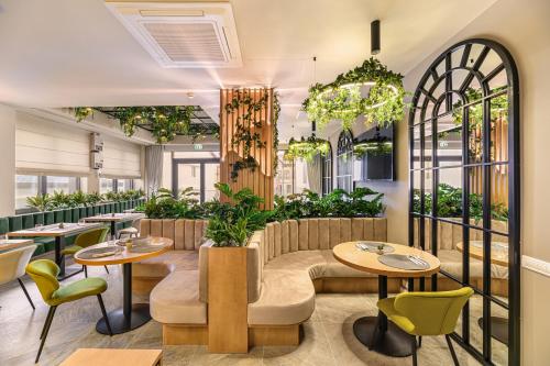 un restaurant avec des tables, des chaises et des plantes dans l'établissement Hotel DUKAT, à Gura Humorului