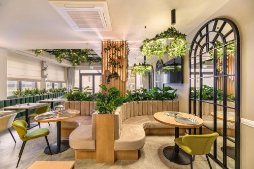 um restaurante com mesas, cadeiras e plantas em Hotel DUKAT em Gura Humorului