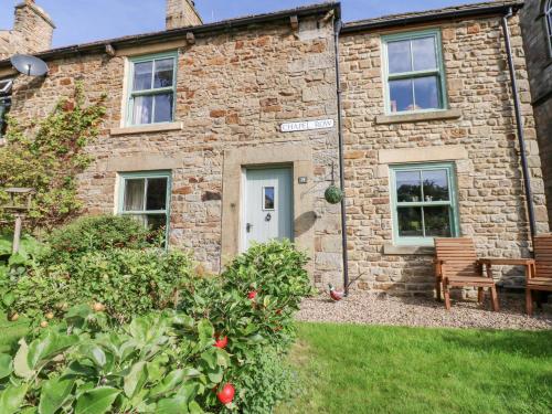 a brick house with a bench in front of it at Chapel Cottage in Barnard Castle