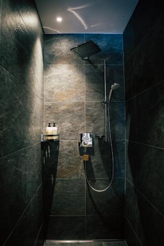 a bathroom with a shower with black tiles at Wagner's Aparthotel in Pertisau