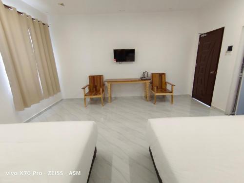 Habitación con mesa, 2 sillas y TV. en ASM Roomstay-4-2 Queen Beds en Kuala Terengganu