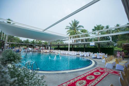 einen Pool mit weißen Stühlen und einem Pool in der Unterkunft โรงแรมแสงทองรีสอร์ท in Ban Nam Mong