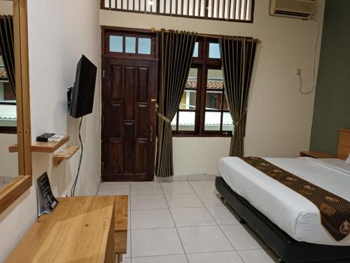 a bedroom with a bed and a television and a door at Shafira Hotel Yogyakarta in Ngabean