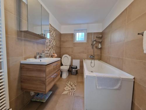 a bathroom with a tub and a toilet and a sink at Sabina's Cozy House in Buşteni