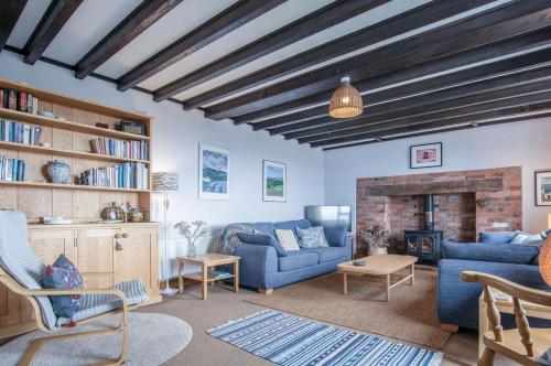 a living room with a blue couch and a fireplace at Windy Walls - 3 Bedroom Holiday Home - Rhossili in Rhossili