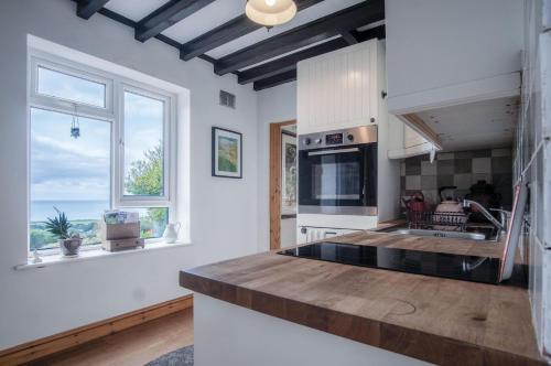 a kitchen with white walls and windows and a counter top at Windy Walls - 3 Bedroom Holiday Home - Rhossili in Rhossili