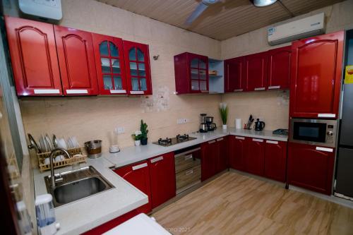 a kitchen with red cabinets and a sink at Irofo City Apartments in Accra