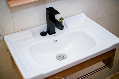 a white bathroom sink with a black faucet at Irofo City Apartments in Accra
