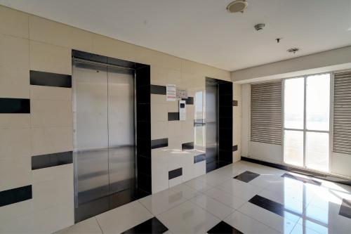 La salle de bains est pourvue de carrelage noir et blanc et d'une porte en verre. dans l'établissement OYO Life 92889 Apartement Grand Sentraland Karawang By A.t Room, à Karawang