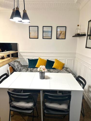 - une table à manger blanche avec des oreillers jaunes et bleus dans l'établissement Charmant 3 pièces Champs-Elysées, Ternes, Porte Maillot, 17ème, à Paris