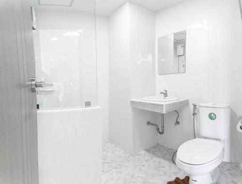 a white bathroom with a toilet and a sink at Sananwan Hometel in Ban Bang Phli Yai