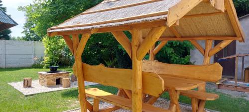 a wooden gazebo with a bench in a yard at Akácfa Vendégház in Makó