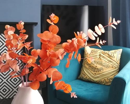eine blaue Couch mit Kissen und eine Vase mit Blumen in der Unterkunft 5-Bedroom Townhouse - Ideal for Groups, Families or Contractors by Glos Homes Ltd in Cheltenham