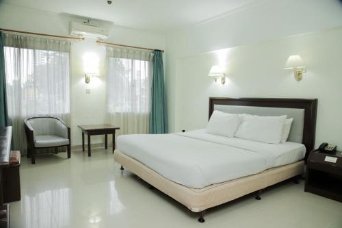 a bedroom with a bed and a table and a chair at Grand Inna Medan in Medan