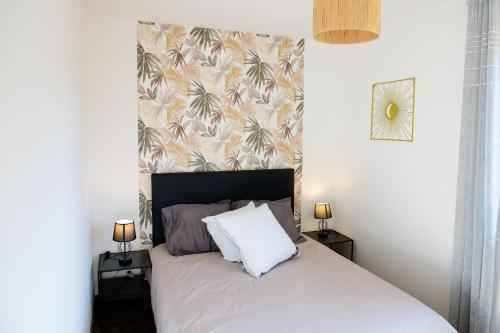 a bedroom with a white bed with a tropical wallpaper at Le Forez Appartement 4 pers ou Studio 2 pers in Cuzieu