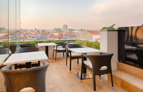 a patio area with tables, chairs and umbrellas at Hotel Premium Porto Downtown in Porto