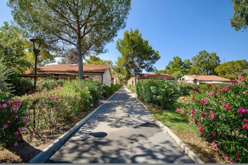 Una pasarela en un jardín con flores en ISA-Appartament plus with mezzanine, 4 beds, air conditioning and private outdoor area in Village with 6 swimming-pools en Piombino