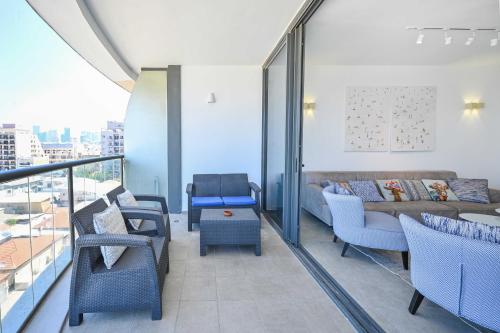 een woonkamer met een bank en stoelen op een balkon bij Granite 2BR by HolyGuest in Tel Aviv