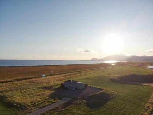 an aerial view of a building in a field next to the ocean at Vatnsholt in Snæfellsnes - Birta Rentals in Snæfellsbær