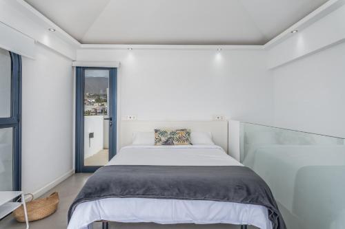a white bedroom with a bed and a window at TORREÓN FRENTE AL MAR in Adeje