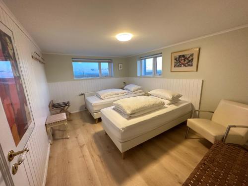 a bedroom with two beds and a chair in it at Vatnsholt in Snæfellsnes - Birta Rentals in Snæfellsbær