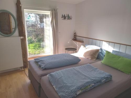 two beds in a bedroom with a mirror and a window at Lütt Logis in Grödersby in Grödersby
