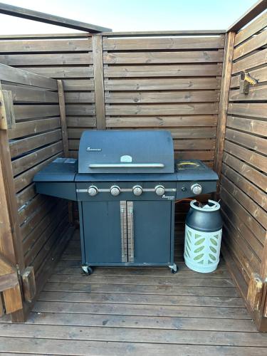 a blue grill sitting on a deck with a trash can at Vatnsholt in Snæfellsnes - Birta Rentals in Snæfellsbær