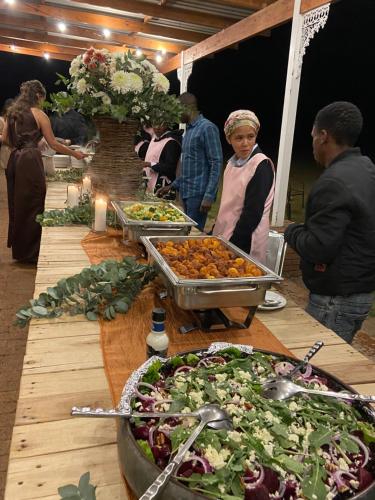 a group of people standing around a table with food at Out Of Nature Country Lodge in Windhoek