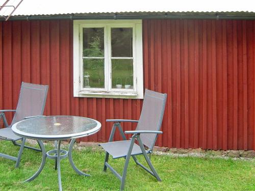 een tafel en stoelen voor een rode muur bij 6 person holiday home in Osby in Osby
