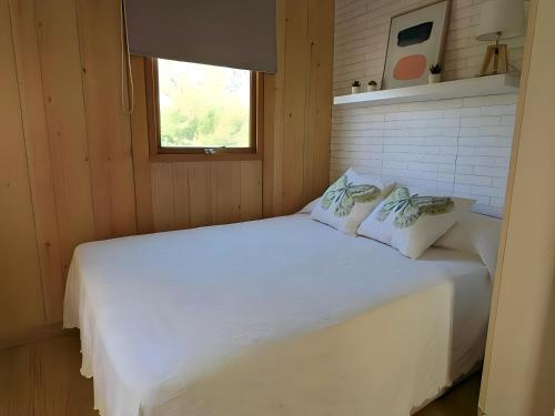 een wit bed in een kamer met een raam bij Bungalow para familias y parejas in Conil de la Frontera