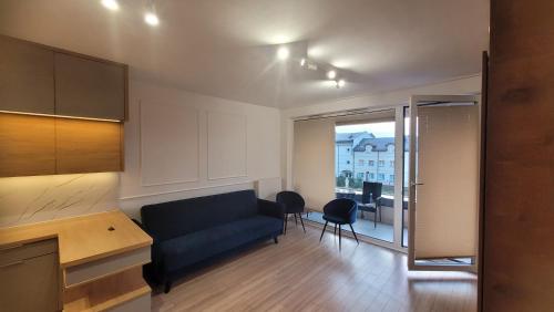 a living room with a blue couch and a kitchen at Queen Apartament Centrum z garażem in Mińsk Mazowiecki
