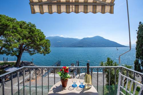una mesa con 2 botellas de vino y flores en el balcón en Casa al Lago Apartments - Brissago Experience, en Brissago