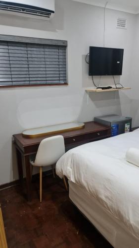 een slaapkamer met een bureau, een bed en een computer bij Suprime Hotels and Conference in Pietermaritzburg