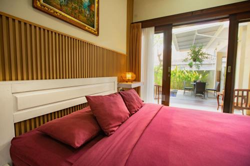 - une chambre avec un grand lit et une couverture rose dans l'établissement Happy Devi Guesthouse, à Canggu