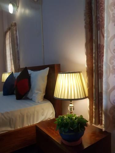 a bedroom with a bed and a table with a lamp at Bloom Garden Bed & Breakfast in Siem Reap