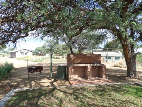 a brick fireplace in a park under a tree at Out Of Nature Country Lodge in Windhoek