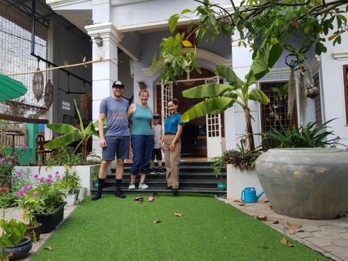 a family standing in front of a house with artificial grass at Bloom Garden Bed & Breakfast in Siem Reap